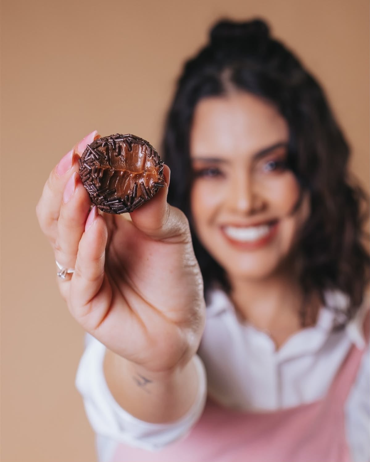 Mariana Lopes, confeiteira fundadora da Doce Encanto, segurando um brigadeiro